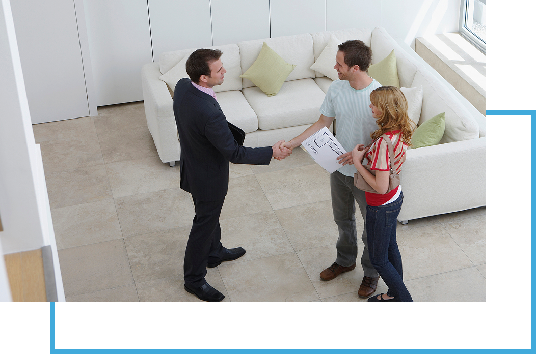 Group 25 A man shaking hands with two people in front of a couch.