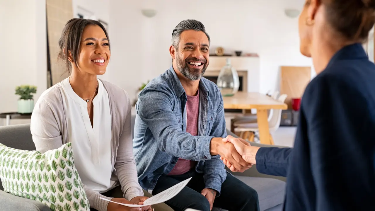 A man shaking hands with another person in front of two women.